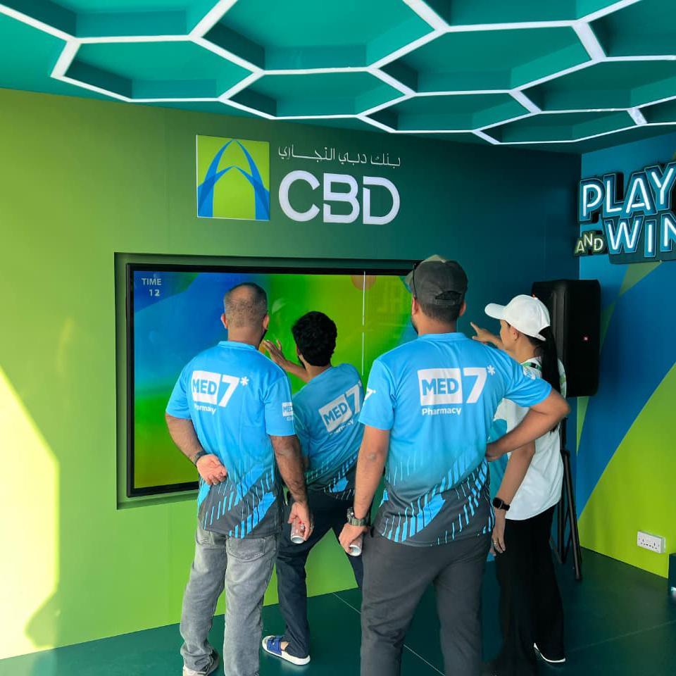 Interactive multi-level touch screen game rental at Dubai 30x30 event, showing guests engaged in a gamified fitness and financial literacy challenge.